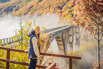 Montenegro. Woman touriste in background of Dzhurdzhevich Bridge Over The River Tara foggy morning....