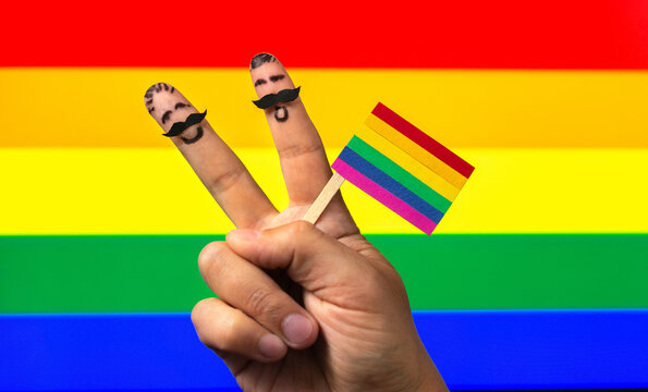 the hands with two fingers men holding rainbow flag, peace sign. international day against homophobia, transphobia and biphobia
