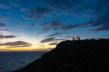 Beautiful sunset over the cliff of The Temple of Poseidon at Cape Sounion, over the Aegean Sea Greece