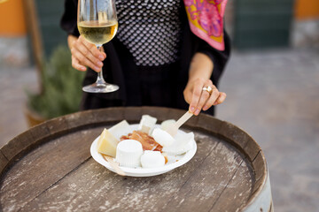 Woman tasting different kind of cheese and wine at local farm shop of Italy, close-up view on a plate. Concept of italian cuisine and local farming