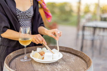 Woman tasting different kind of cheese and wine at local farm shop of Italy, close-up view on a plate. Concept of italian cuisine and local farming