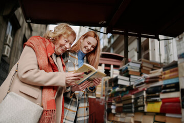 A grandmother and granddaughter choosing books at bookstore.