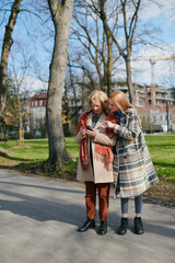 Fototapeta premium A grandmother and her grandchild standing on the street and reading messages on the phone.