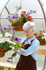 Old happy woman with white hair smile and take care flowers in her garden portrait.