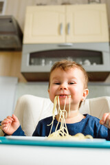 Little girl likes to eat spaghetti by herself.