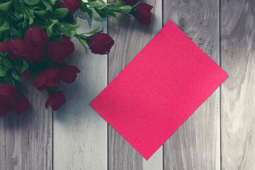 Red note on wooden surface and red roses bouquet flat lay with copy space