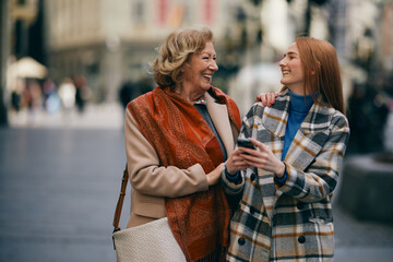 A grandmother and her grandchild standing on the street and reading messages on the phone.