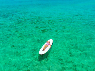 Maldives islands travel. Beautiful woman on a surf board is sunbathing in a bikini. Maldives beaches tourist paradise  - 506834605
