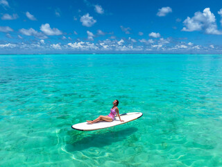 Beautiful woman on a surf board is sunbathing in a bikini. Maldives beaches  tourist paradise.
Travel Maldives islands - 506834608