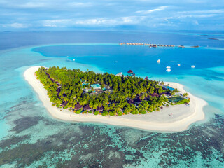 Aerial view of Maldives island, luxury water villas resort and wooden pier. Beautiful sky and ocean...
