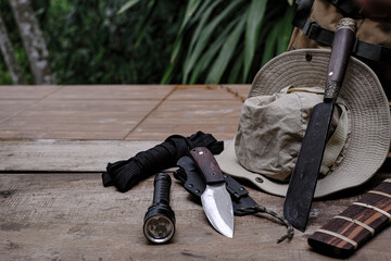 A knife with equipment for survival in the forest  on an old wooden floor