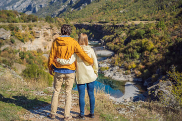 Montenegro. Happy couple man and woman tourists on the background of Clean clear turquoise water of river Moraca in green moraca canyon nature landscape. Travel around Montenegro concept