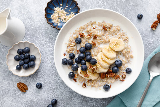 Oatmeal porridge with banana, blueberries, pecan nuts and sesame seeds