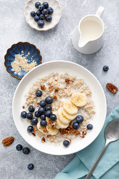 Oatmeal porridge with banana, blueberries, pecan nuts and sesame seeds