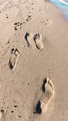 Footprints on the beach sand. Summertime sea. Footprints near the wave water. 