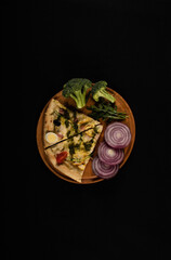 Isolated wooden board with pizza, broccoli and onions.  View from above. Pizza on black background. 