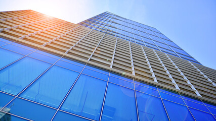 Facade of modern glass building at sunset. Warm and cool tone contrast. Sun flare.