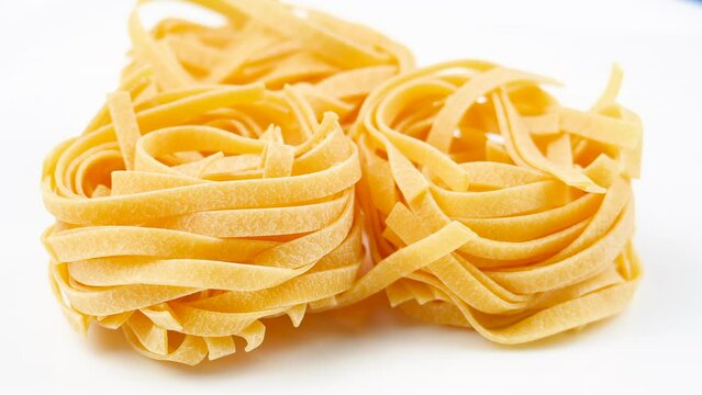 Background Of Tagliatelle Pasta. Uncooked Italian Pasta Golden Rotating Backdrop. Healthy Eating Concept. Raw Dried Organic Pasta. Spiral Macaroni, Rotating Background. Italian Culture and Cuisine 