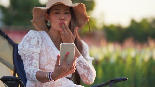 young girl visits an online dating site via chat on her phone at the flower garden.