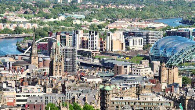 Multiple church tower with the high Millennium Bridge soars over the River Tyne and the ultra modern Sage Gateshead in the Newcastle city skyline. Drone dolly shot