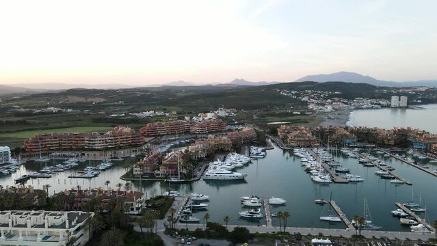 Drone footage of the beach and port of Sotogrande. Amazing views of the shore and yachts at the marina. Aerial view during sunset in 4K.
