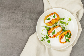 Baked accordion potatoes with fresh green pea sprouts.Traditional American food, homemade vegan diet