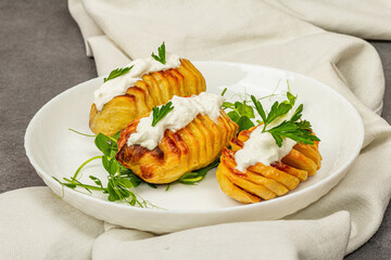 Baked accordion potatoes with fresh green pea sprouts.Traditional American food, homemade vegan diet
