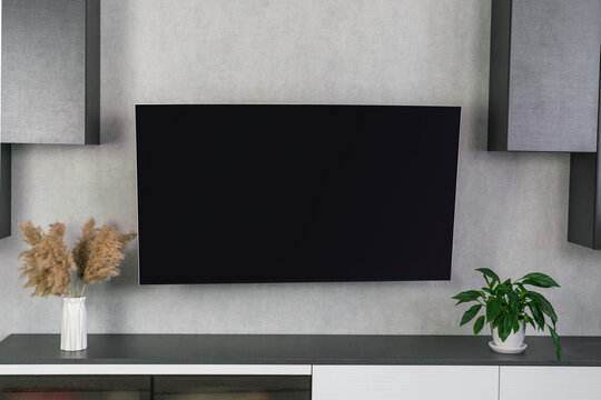 Television black empty screen slightly curved and that has slim casing hanging on wall at living room