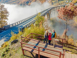 Montenegro. Happy family on the background of Dzhurdzhevich Bridge Over The River Tara foggy morning