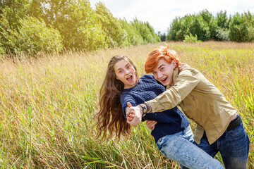 Naklejka na ściany i meble Summer holidays vacation happy people concept. Loving couple having fun together in nature outdoors. Happy young man dancing hugging with his girlfriend. Happy loving couple outdoor at summertime