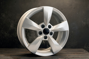 new grey alloy wheels on a dark textured black background. a wheel for a car