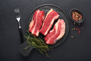 Steak beef. Raw steak New York with rosemary and spices on old iron plate on old dark stone background. Top view. Mock up.