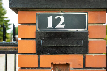House number 12 above letterbox in fence