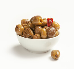 grilled green olives in oil, pitted, with red hot pepper and garlic in a white bowl on a light...