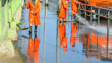 Work janitors wash the sidewalk with a stream of water from a hose on the Moscow Highway on a...
