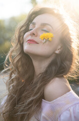 curly hair woman with blue eyes and yellow flower on face