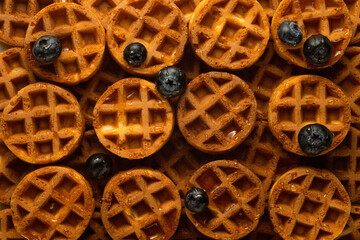 Soft round fried waffles on a beige background. Monochrome pattern with hard shadows.
