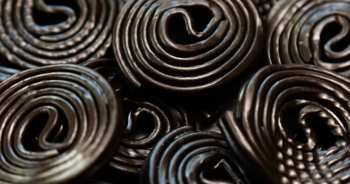 Rotation of Flat lay tasty black liquorice candies on black background, Candy flavored licorice, top view.