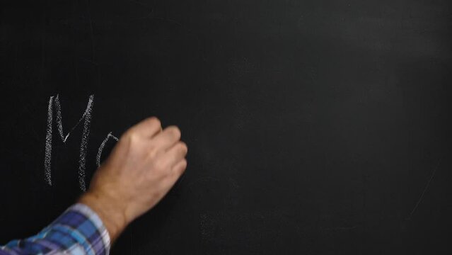 A man writes the word Monkeypox on a black board with white chalk and hangs up a protective mask. The concept of a monkeypox outbreak. A new global epidemic