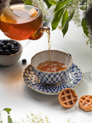 Pouring black tea into glass cup on marble table
