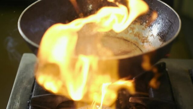 Close up of cooking food with flame in a frying pan. Slow motion.4K. Chef is tossing chicken meat on a pan.Cooking flambe style chicken .