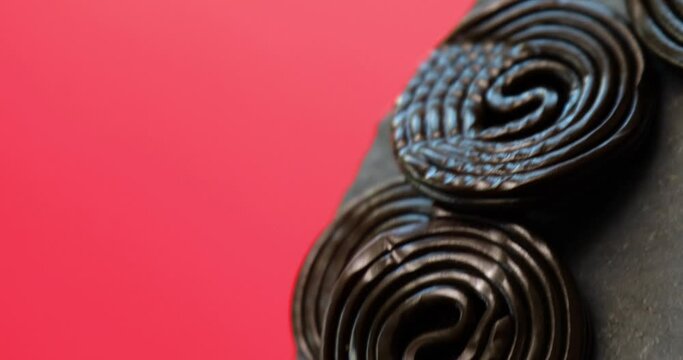 Rotation of Flat lay tasty black liquorice candies on red background, Candy flavored licorice, top view.