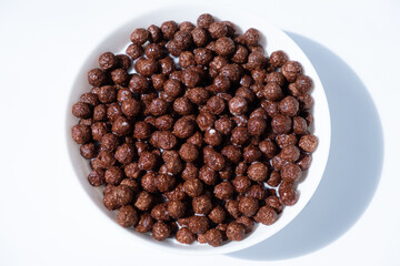 chocolate granules balls in milk in a white plate for breakfast

