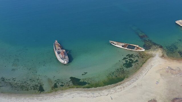 Abandoned wooden hunting schooner Lakhtak built in 1953 in Vityaz Bay. A wrecked wooden ship lies on the seashore, covered with rust. Drone view