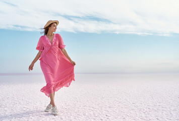 Adorable romantic woman admiring serenity colorful landscape of salt flats on pink lake. Girl...
