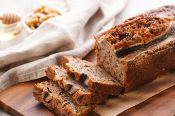 Chocolate banana bread with walnuts on a wooden board and ingredients on a grey neutral background