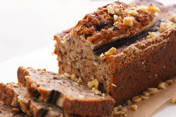 Chocolate banana bread with walnuts on a marble board and ingredients on a grey neutral background