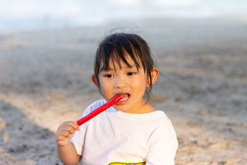 Portrait image of 4-5 years old childhood. Asian child happy girl eating a food on the beach. At the sea. Summer season.