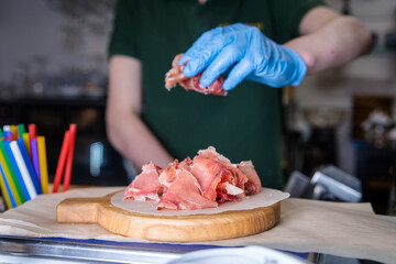 Sliced jamon on a wooden board. A man in a glove cuts a jamon.