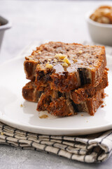 Slices of Chocolate banana bread with walnuts on a checkered kitchen napkin and ingredients on a grey neutral background